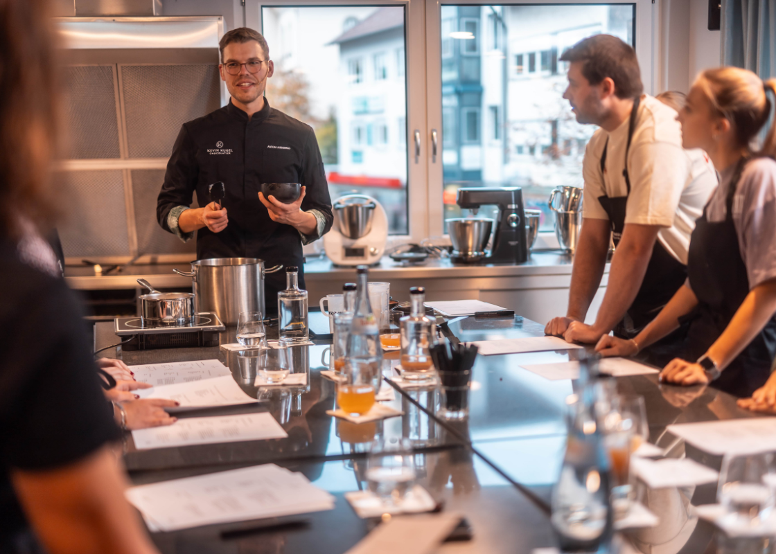 Die Teilnehmer stehen um einen Tisch und schauen zum Chefpatissier.
